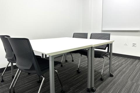 Photograph of small study room with a table, four chairs, and a whiteboard