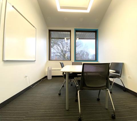 Photo of small study room with two windows, a table, chairs, white board