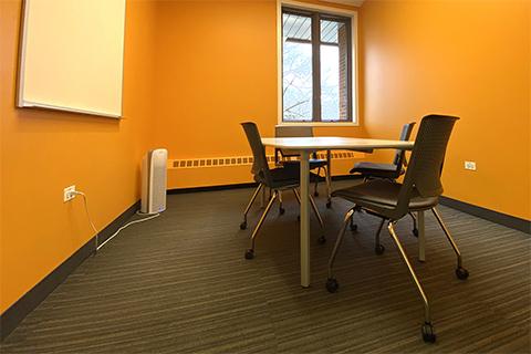 Photograph of small room with table, four chairs, whiteboard, window