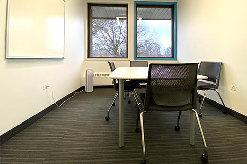 Photo of small study room with two windows, a table, chairs, white board